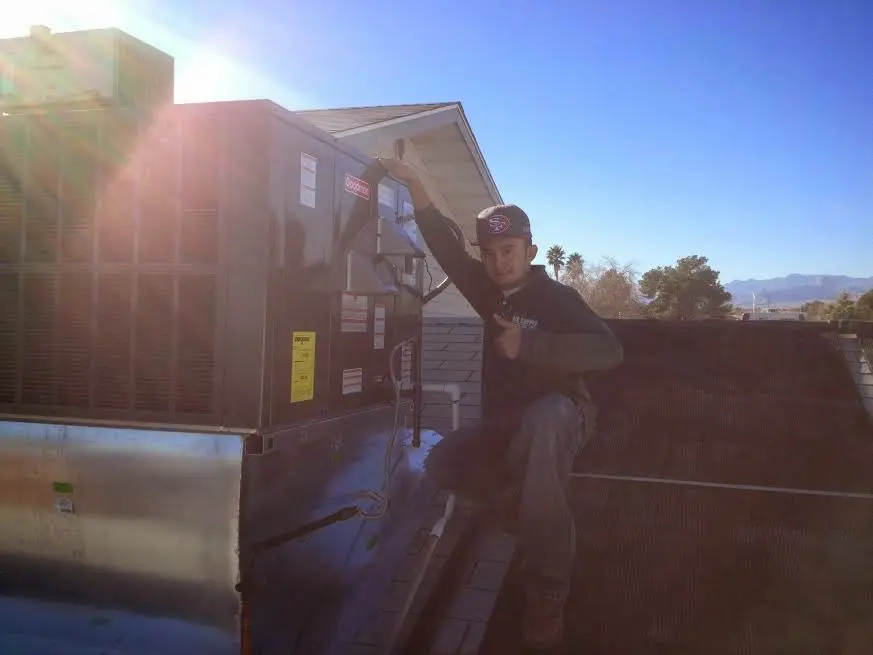HVAC technician performing Heat Pump Repair on a rooftop unit in Laurinburg